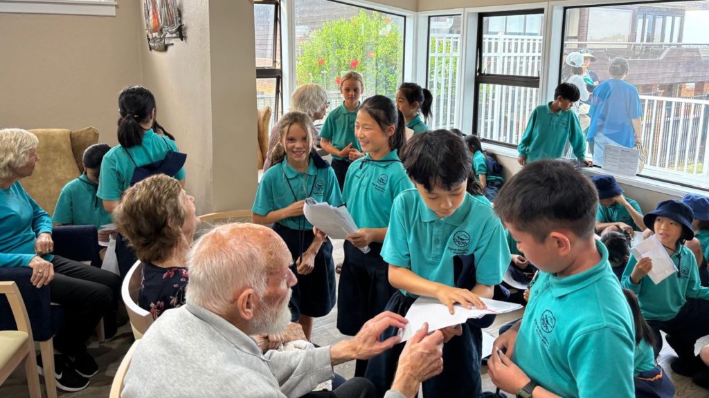 Primary school students sing to elderly people